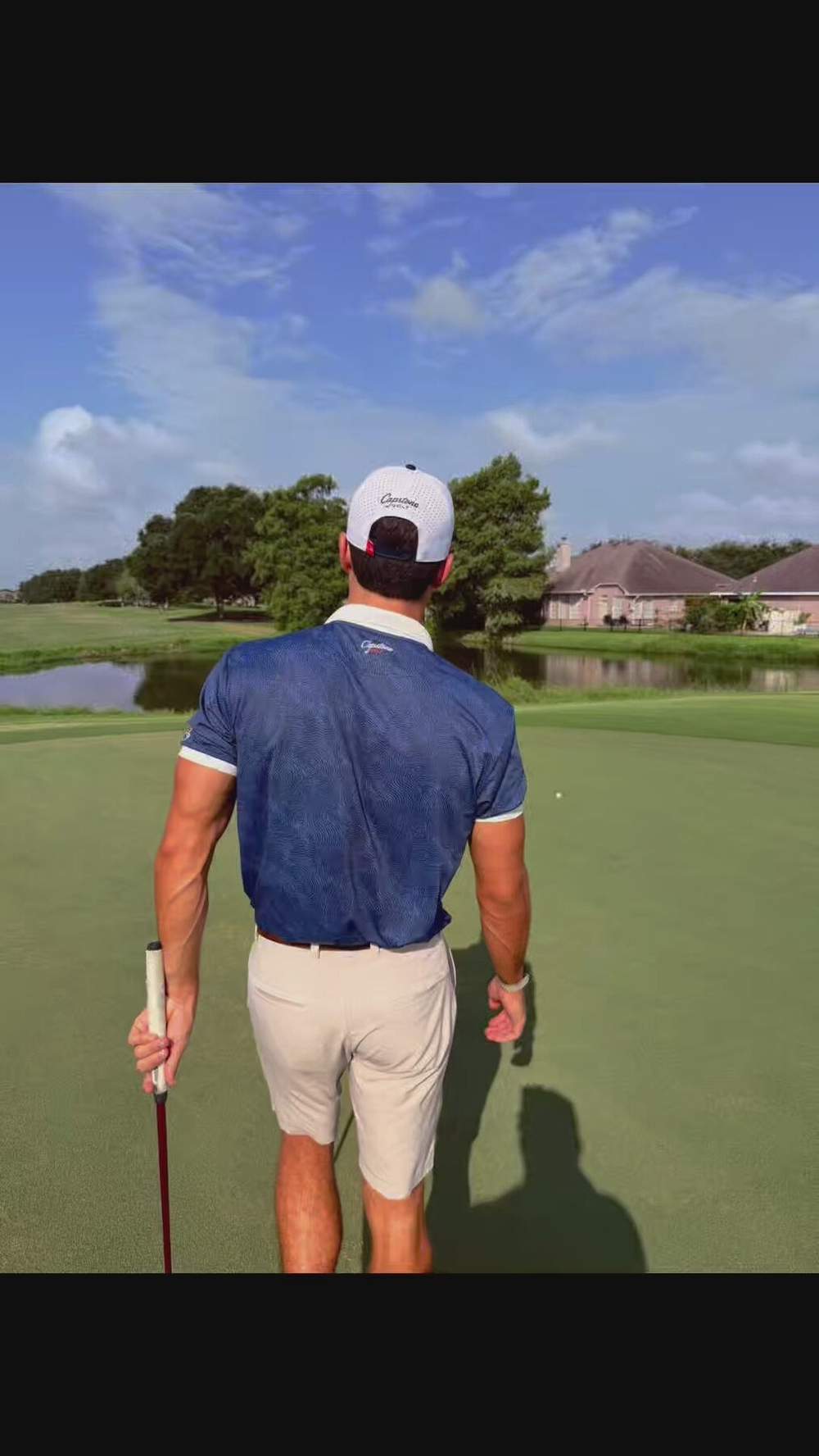 Capstone Golf ambassador walking the green with the flagstick, wearing a Capstone performance rope hat and polo